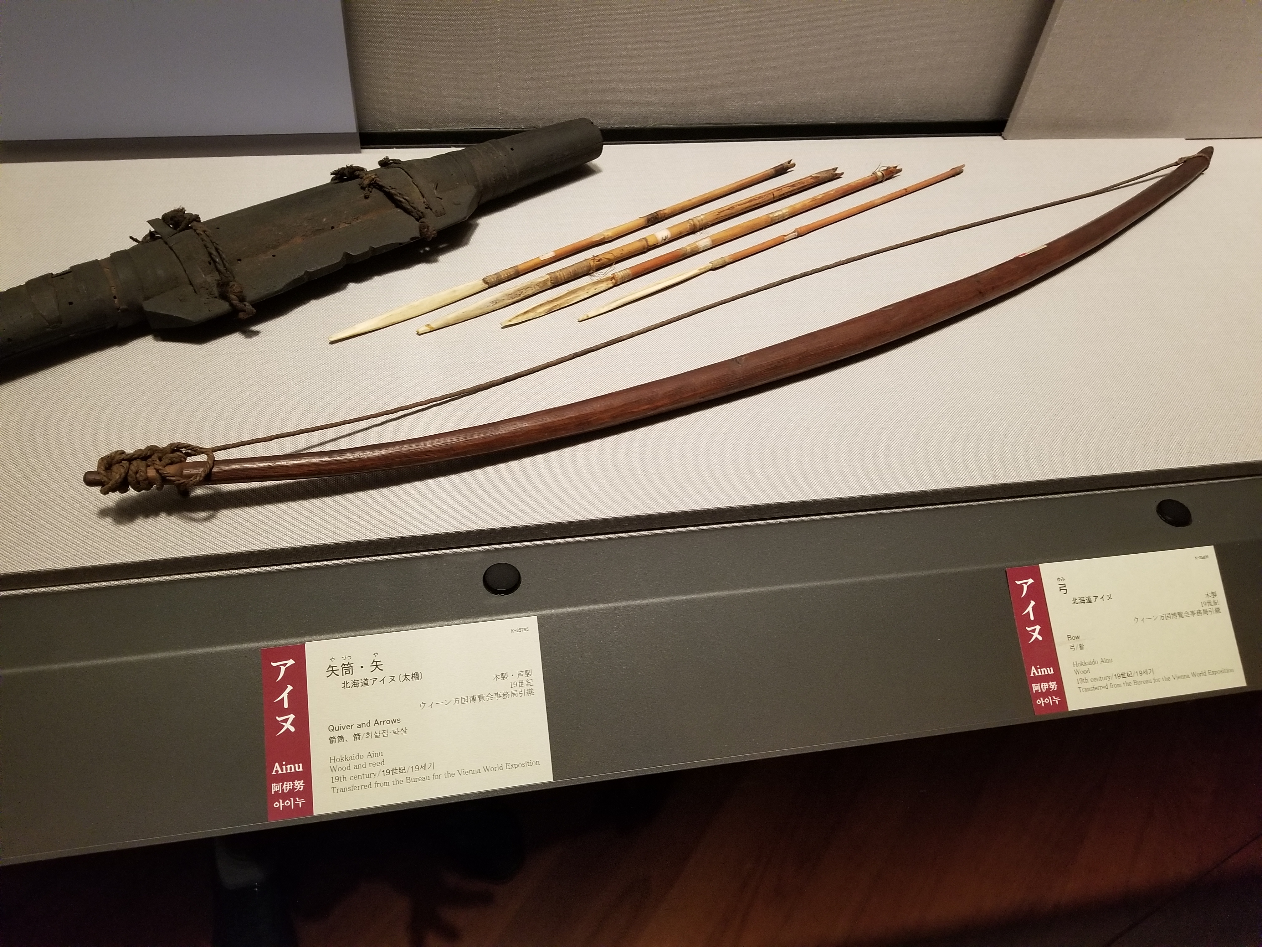 A large bow and several arrows and a holster on display.